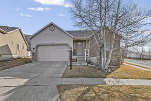 View of front of property featuring a garage, concrete driveway, stone siding, and stucco siding