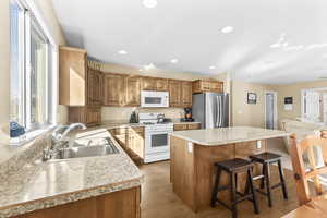 Kitchen with a kitchen island, white appliances, a breakfast bar area, open floor plan, and light countertops