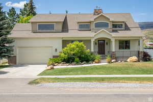 View of front of house with covered porch, a shingled roof, a front yard, and driveway