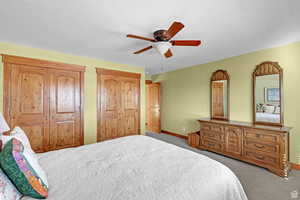 Bedroom with carpet floors, two closets, and ceiling fan