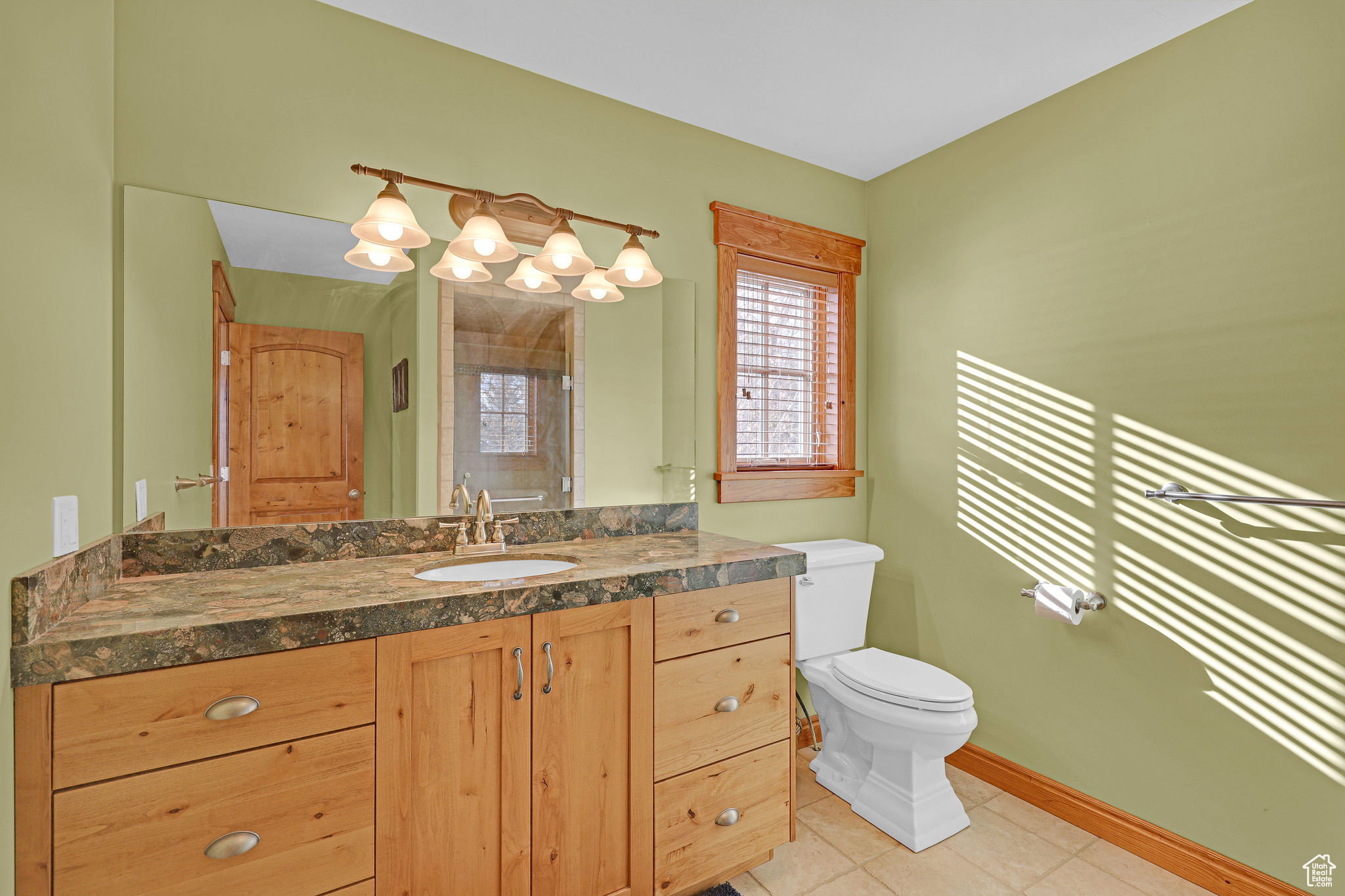 Bathroom featuring vanity, light tile patterned floors, and a shower with shower door