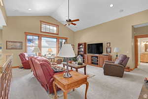 Living room with high vaulted ceiling, light carpet, and a ceiling fan