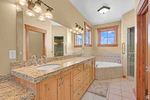 Full bath featuring a shower stall, double vanity, a bath, and light tile patterned flooring
