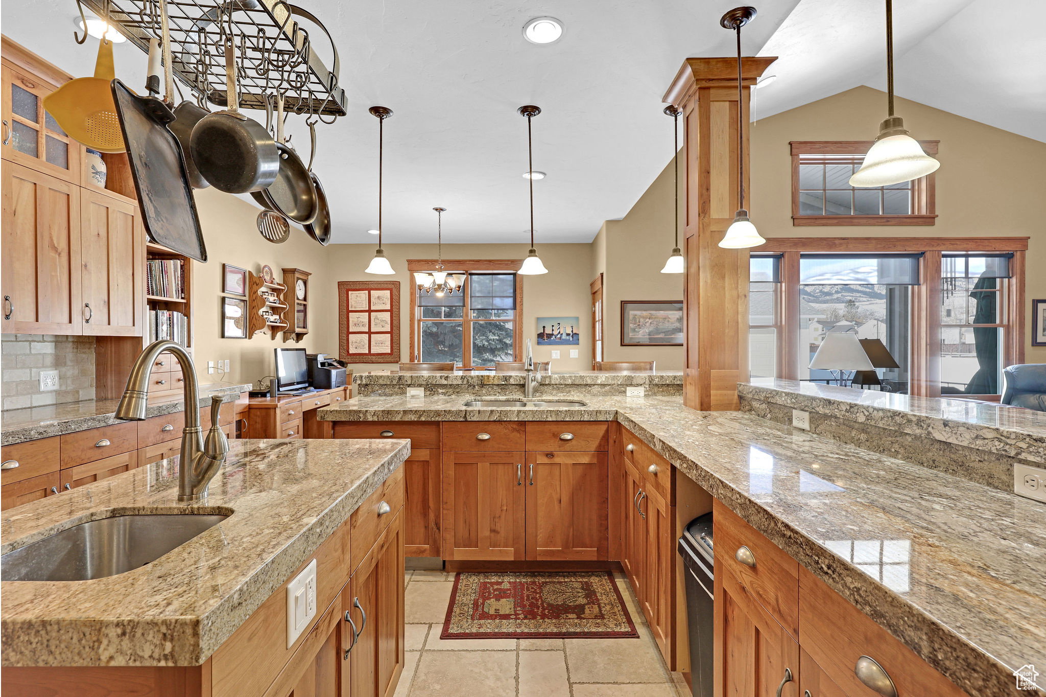 Kitchen featuring hanging light fixtures, brown cabinets, tasteful backsplash, glass insert cabinets, and vaulted ceiling