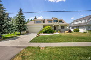 View of front of property featuring concrete driveway, a chimney, a shingled roof, and covered porch