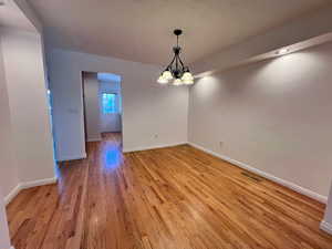 Unfurnished room featuring hanging lights and light wood-type flooring