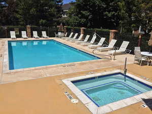 Community pool with a patio area and a hot tub