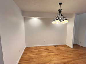 Unfurnished dining area with light wood-style floors and a chandelier