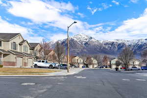 View of asphalt street with sidewalks, a residential view, street lighting, a mountain view, and curbs