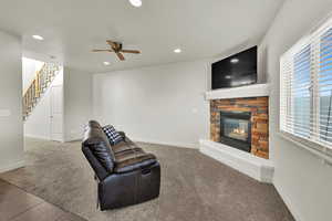 Unfurnished living room featuring light colored carpet, a stone fireplace, recessed lighting, and ceiling fan