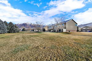 Rear view of property featuring a mountain view, brick siding, and a lawn