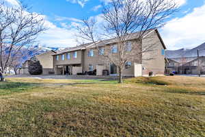 Back of house featuring a lawn, a mountain view, and a patio area