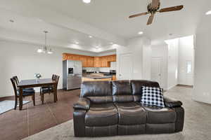 Living room featuring suspended lighting, a ceiling fan, and dark tile patterned flooring