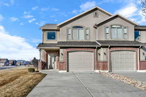 View of front of property featuring concrete driveway, a garage, and a shingled roof