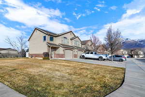 View of side of property with brick siding, a yard, a garage, a residential view, and concrete driveway