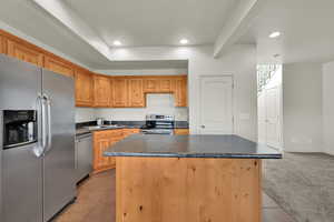 Kitchen featuring stainless steel appliances, a kitchen island, dark countertops, recessed lighting, and light tile patterned floors