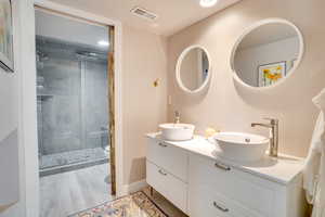 Full bath featuring double vanity, a shower stall, light wood-type flooring, and recessed lighting