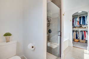 Full bathroom with a shower stall, a spacious closet, and tile patterned flooring