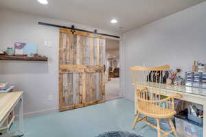 Office space featuring a barn door, concrete floors, and recessed lighting