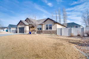 View of front of house with stone siding, a garage, driveway, and stucco siding
