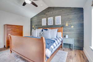 Bedroom featuring wooden walls, an accent wall, wood finished floors, and a ceiling fan