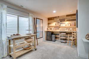Bar featuring light carpet, freestanding refrigerator, recessed lighting, and wooden walls