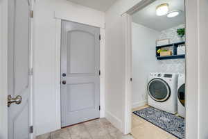 Laundry area with washing machine and clothes dryer and light tile patterned flooring