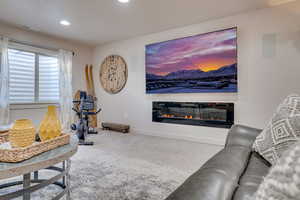 Living room with carpet flooring, a glass covered fireplace, and recessed lighting