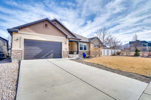 Craftsman-style home featuring stone siding, concrete driveway, a garage, and stucco siding