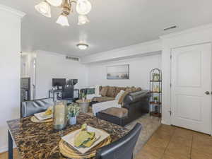 Living room featuring ornamental molding, light tile patterned floors, and suspended lighting
