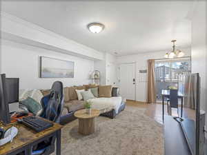 Living room with crown molding, an office area, a chandelier, and light tile patterned floors