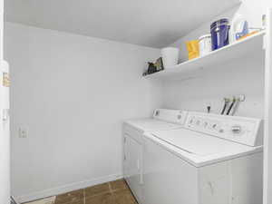 Laundry area featuring dark tile patterned flooring and separate washer and dryer