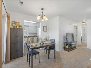 Dining space featuring ornamental molding, a chandelier, and light tile patterned floors