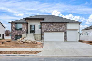 View of front of home featuring stone siding, board and batten siding, driveway, and a shingled roof