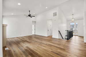 Unfurnished living room featuring light wood finished floors, suspended lighting, vaulted ceiling, and a ceiling fan