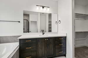 Full bath with a spacious closet, vanity, a shower stall, and a bath