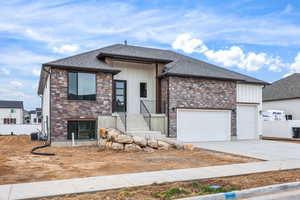 View of front of home featuring stone siding, board and batten siding, driveway, and roof with shingles