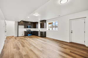 Kitchen with dark wood finish cabinets, light countertops, stainless steel appliances, light wood-type flooring, and recessed lighting