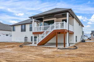 Back of house with a shingled roof and a patio