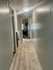 Corridor with light wood-style flooring and wooden walls