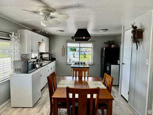 Dining area featuring wooden walls, light wood finished floors, a ceiling fan, and a textured ceiling