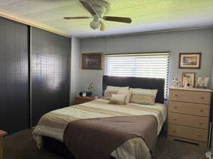 Bedroom with carpet, ceiling fan, and wood walls