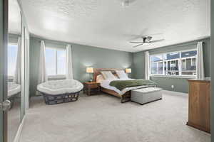 Master bedroom featuring light carpet, a textured ceiling, and a ceiling fan