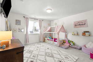 Bedroom with light colored carpet and a textured ceiling