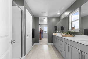 Master bath with a double vanity, walk in shower, and a walk in closet