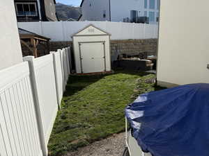 Fenced backyard featuring a shed and a mountain view