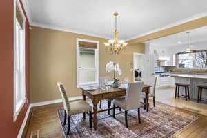 Dining room with a chandelier, crown molding, light wood finished floors, and washing machine and clothes dryer