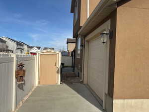 View of home's exterior featuring a garage, a shed, stucco siding, and a residential view