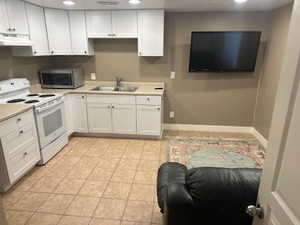 Kitchen featuring electric range, recessed lighting, white cabinets, light tile patterned floors, and light countertops