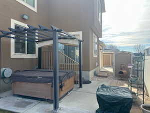 Fenced backyard featuring a hot tub, a patio area, a storage shed, and a pergola